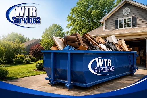 Blue WTR Services dumpster filled with household debris in a residential driveway